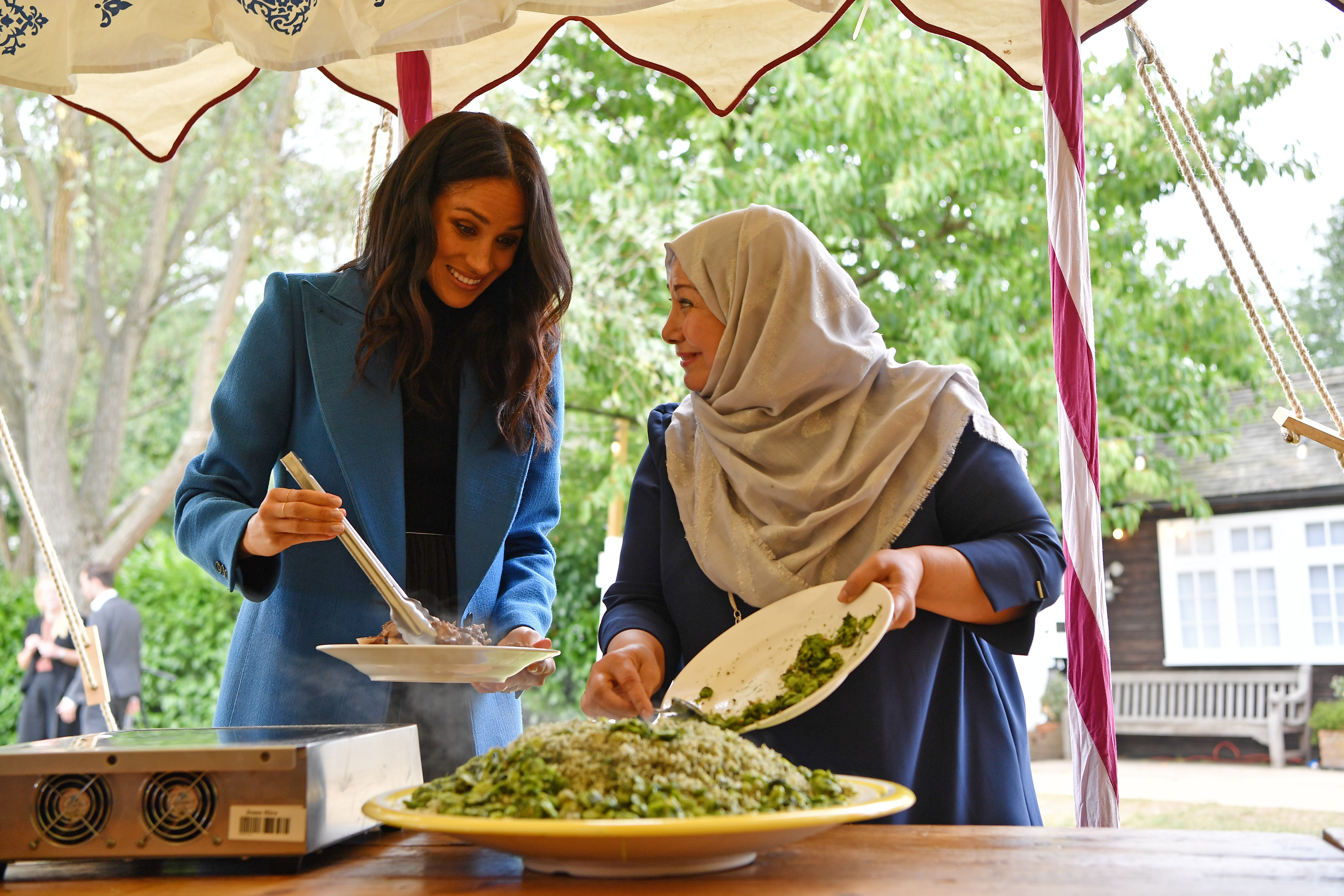 Meghan, Duchess of Sussex helps to prepare food at an event to mark the launch of a cookbook with recipes from a group of women affected by the Grenfell Tower fire at Kensington Palace on September 20, 2018 in London, England.
