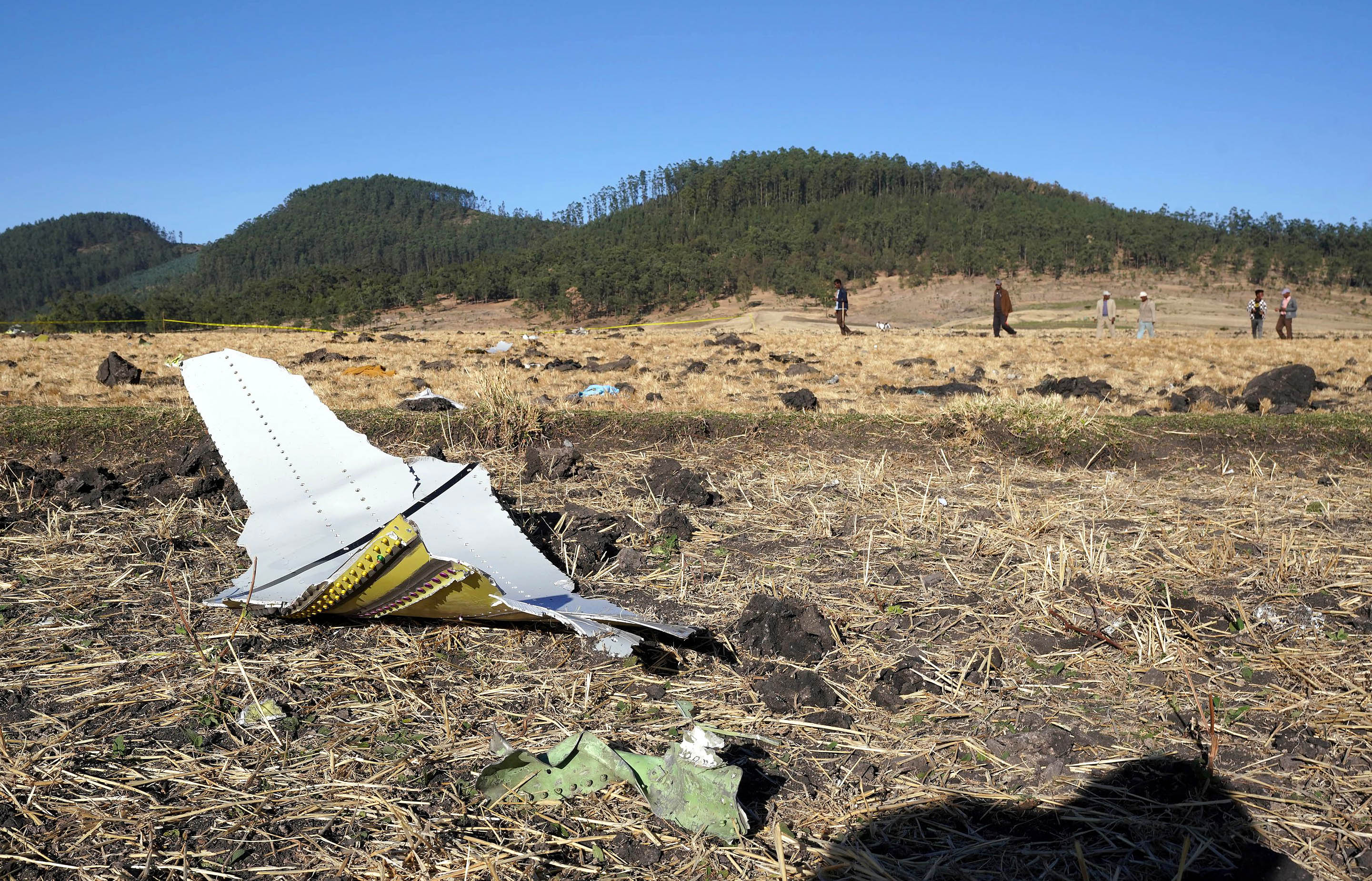 A piece of the fuselage of ET Flight 302 can be seen in the foreground as local residents collect debris at the scene where Ethiopian Airlines Flight 302 crashed in a wheat field just outside the town of Bishoftu, 62 kilometers southeast of Addis Ababa on March 10, 2019, in Addis Ababa, Ethiopia. (Getty)