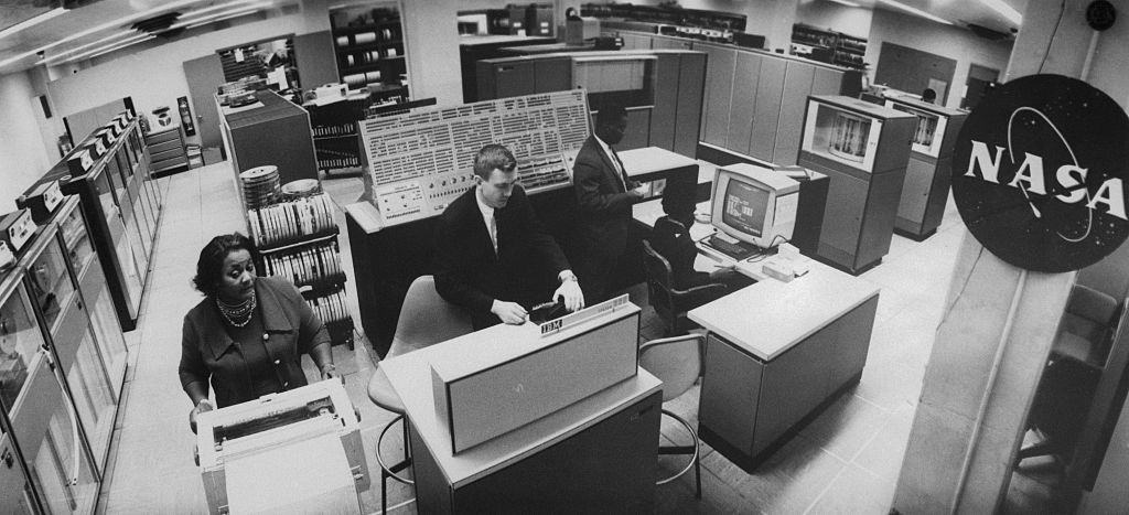 Flanked by a display console with an array of indicator lights and switches, a NASA operator uses a TV-like screen to monitor the work stream of at-the-time the fastest, most powerful computer in operation--the IBM System/360 Model 91.
