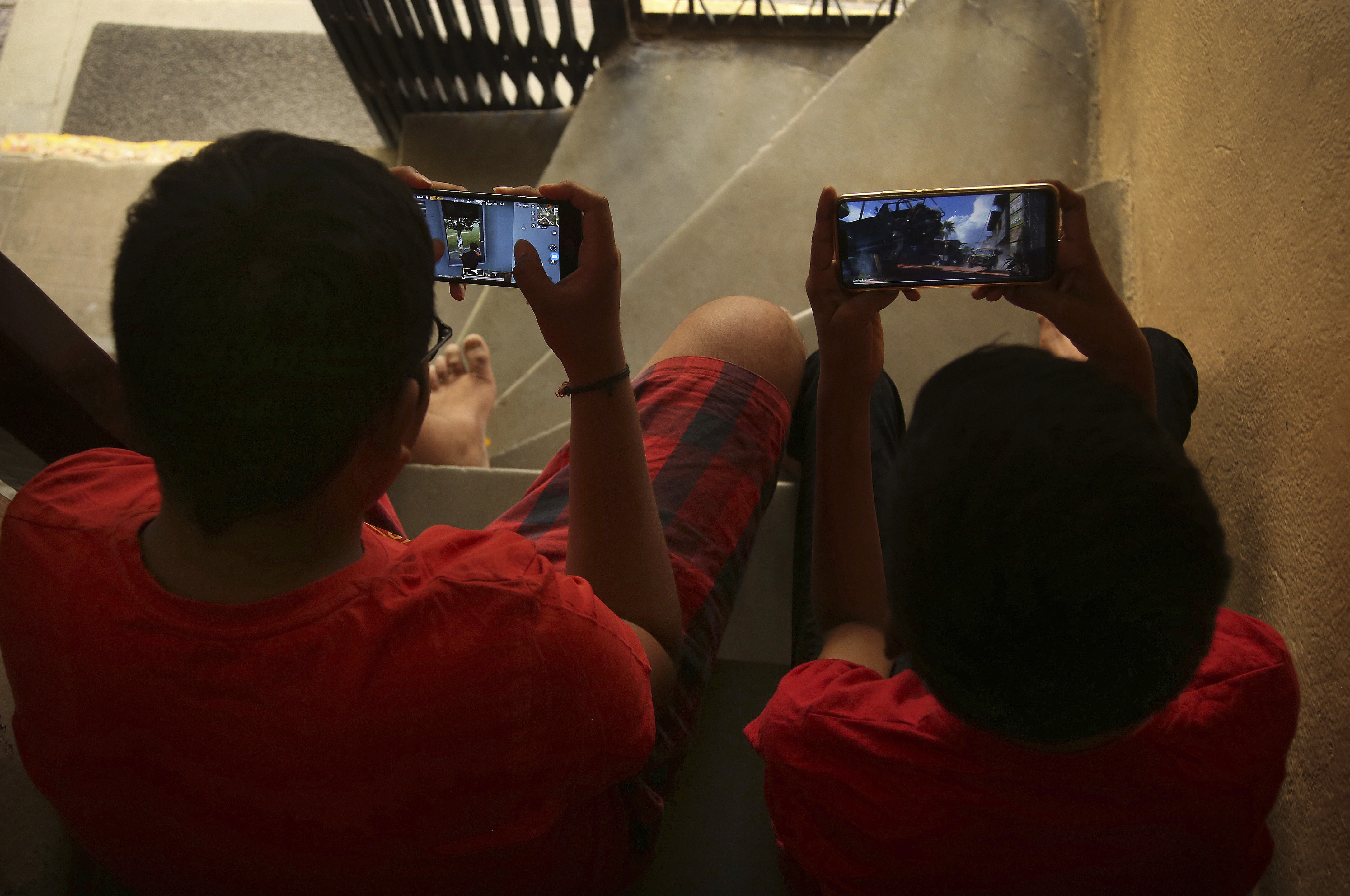 Indian children play online game PUBG on their mobile phones sitting on stairs outside their house in Hyderabad, India, Friday, April 5, 2019. A boy’s suicide in India after his mother scolded him for playing the popular online game PlayerUnknown’s Battlegrounds has inflamed a debate across the country over whether the game should be banned. (AP Photo/ Mahesh Kumar A.)