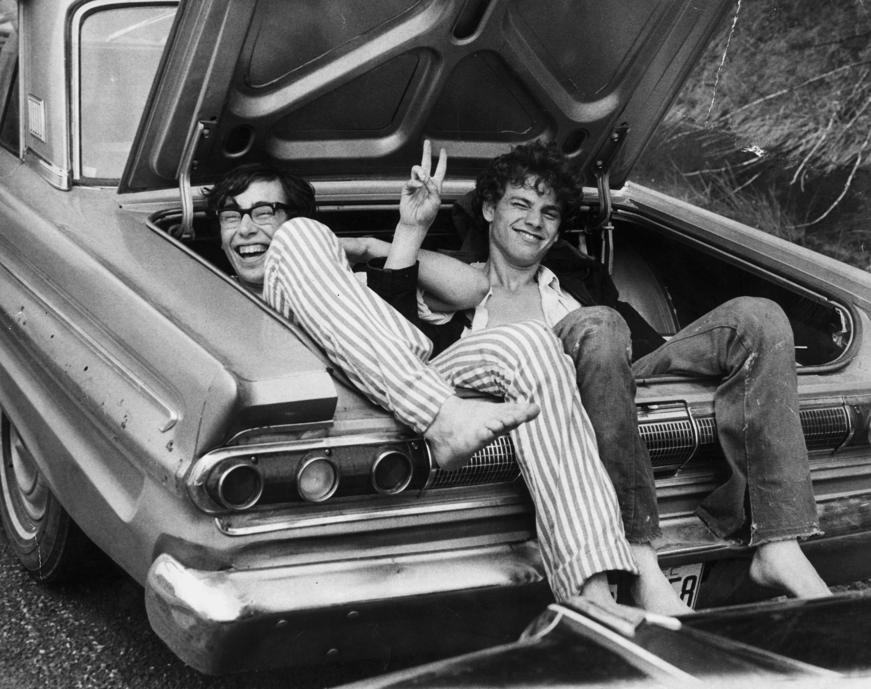 Two young men in the boot of a car after hitching a lift home from the Woodstock Music and Arts Fair.