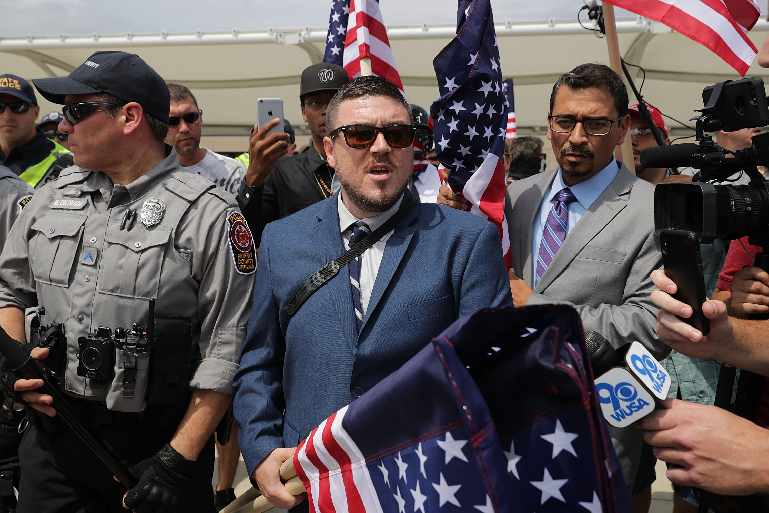 Surrounded by his supporters, reporters and Fairfax County Police, Jason Kessler (C) walks toward the Vienna/Fairfax GMU Metro Station to travel by train to the White House for his white supremacist 'Unite the Right' rally August 12, 2018 in Vienna, Virginia. Thousands of protesters are expected to demonstrate against the 'white civil rights' rally in Washington, which was planned by the organizer of last year's deadly rally in Charlottesville, Virginia.