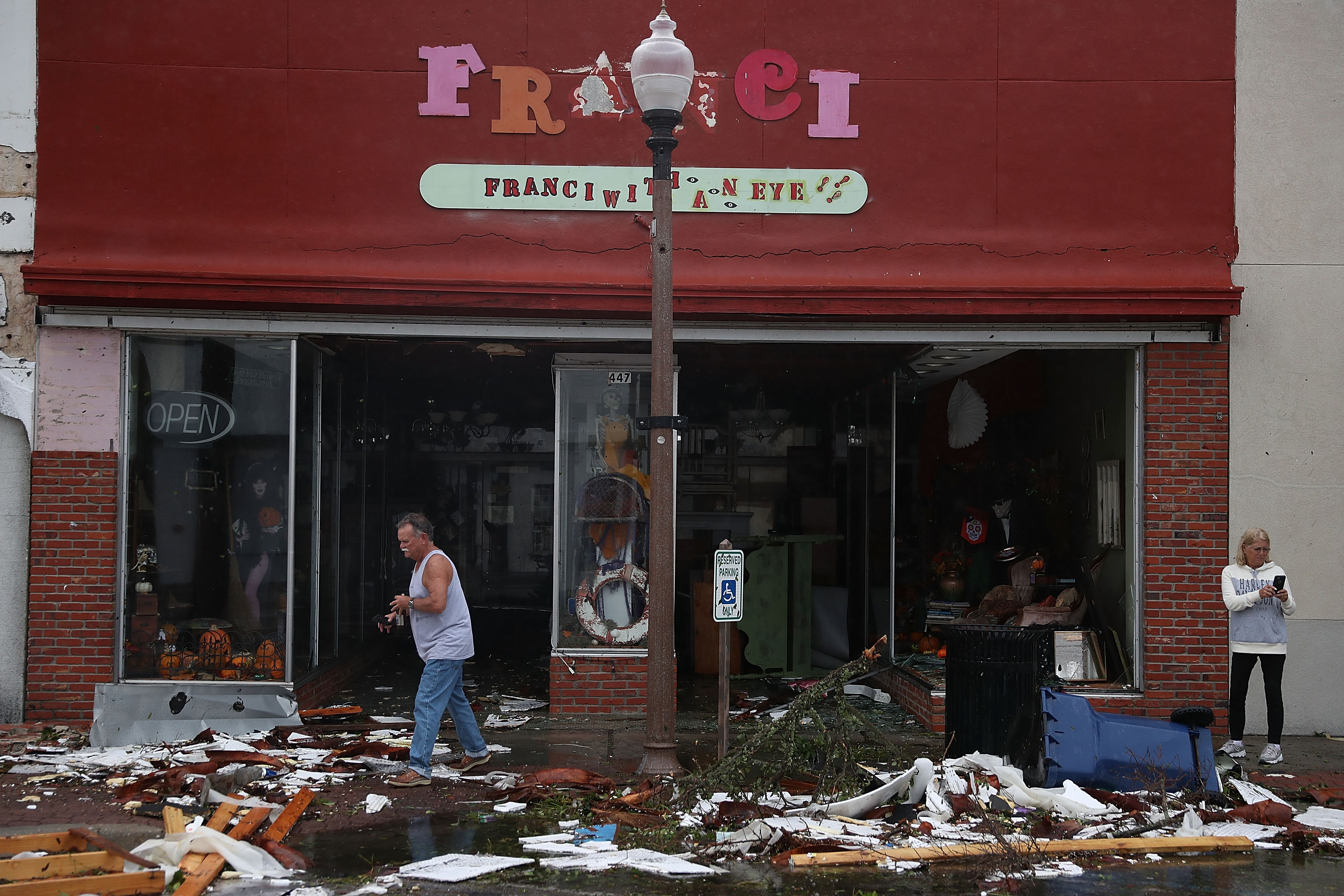 People walk past damaged stores after hurricane Michael passed through the downtown area on October 10, 2018 in Panama City, Florida. The hurricane hit the Florida Panhandle as a category 4 storm.