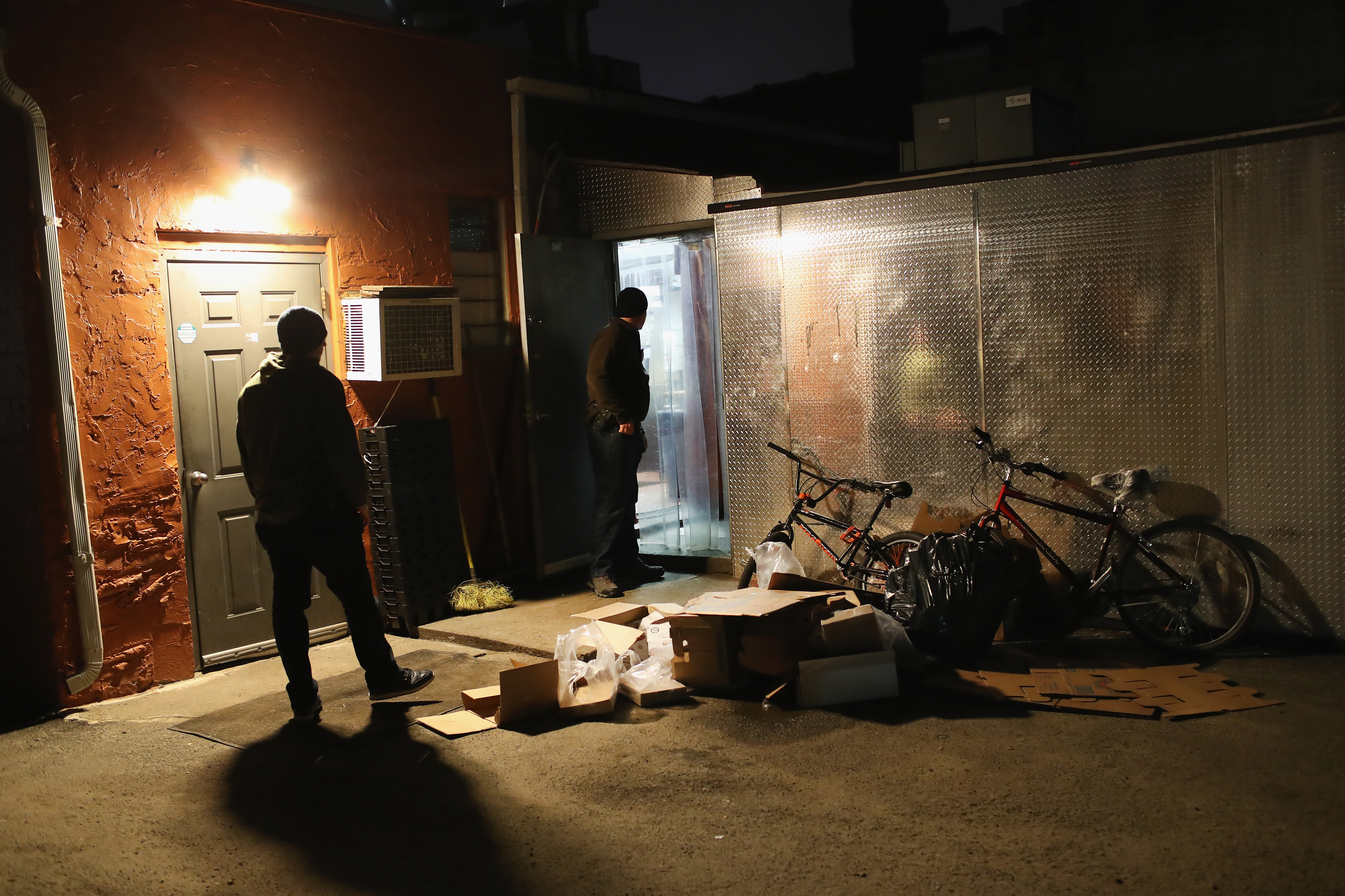 U.S. federal agents watch a back exit as fellow officers detain a suspected gang member late on March 28, 2018, in Hempstead, New York. (Getty)