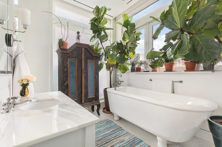The en-suite master bath is outfitted with a marble-topped vanity, a deep soaking tub and a number of tropical plants for effect and ambiance. (Donna Dotan)