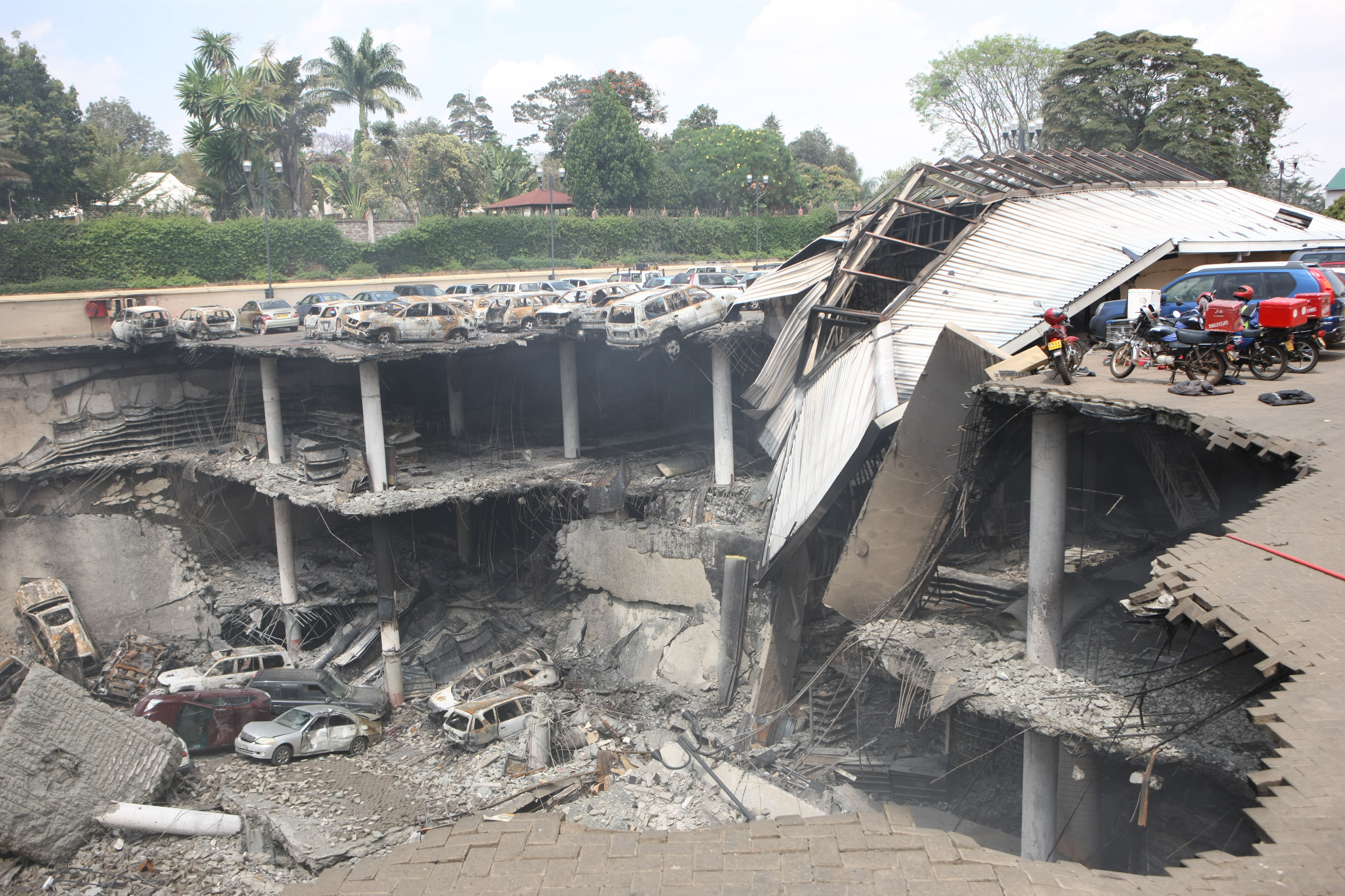 In this handout photo provided by the Kenyan Presidential Press Service, The remains of cars and other debris can be seen in a general view photographed from the rooftop, of the parking lot outside the Westgate Mall on September 26, 2013, in Nairobi, Kenya. The country is observing three days of national mourning as security forces begin the task of clearing and securing the Westgate shopping mall following a four-day siege by militants. (Source: Kenyan Presidential Press Service via Getty Images)