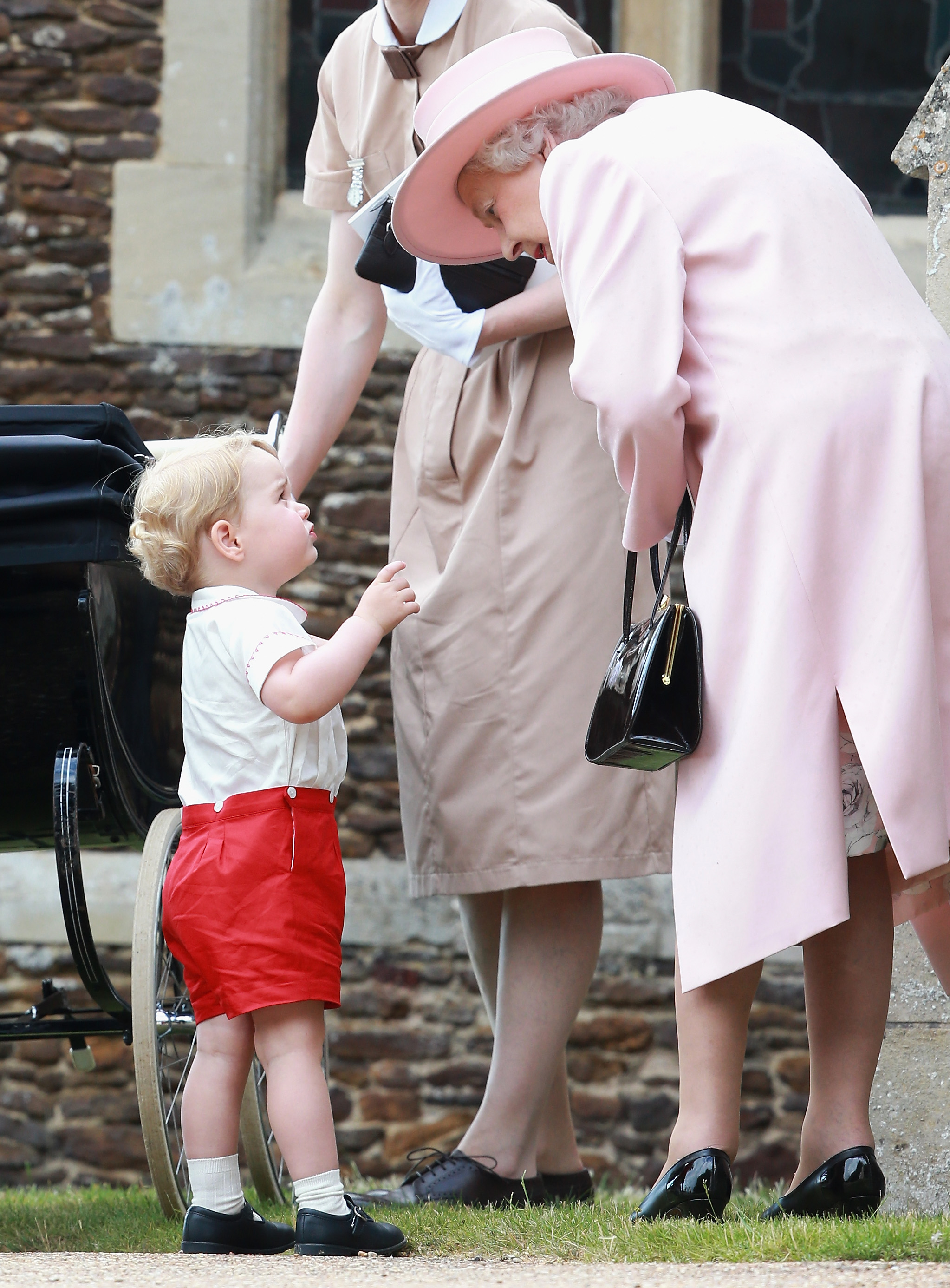 Prince George of Cambridge talks to Queen Elizabeth II outside the Church of St Mary Magdalene on the Sandringham Estate for the Christening of Princess Charlotte of Cambridge on July 5, 2015 in King's Lynn, England.