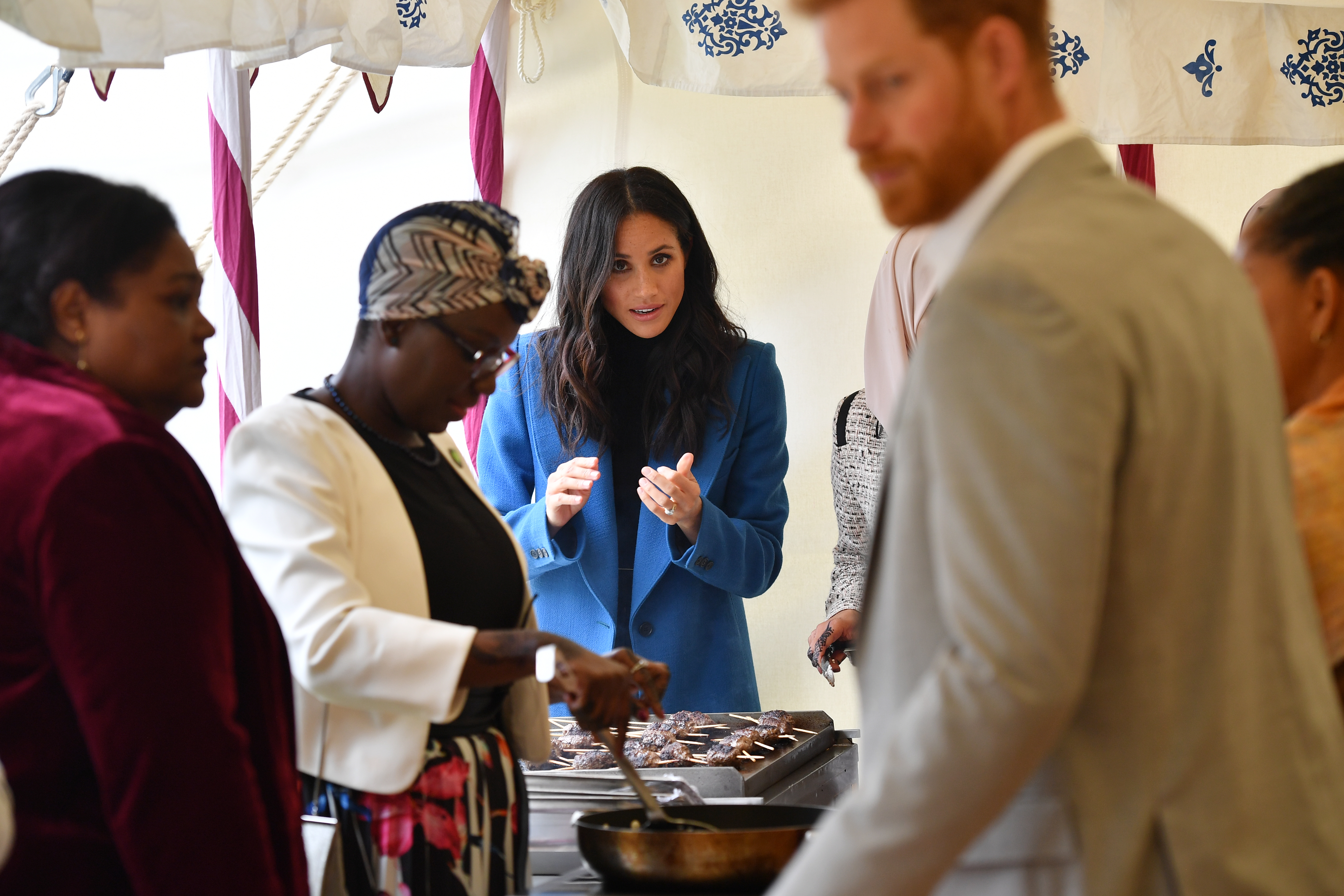 Meghan, Duchess of Sussex (3L) helps to prepare food at an event to mark the launch of a cookbook with recipes from a group of women affected by the Grenfell Tower fire at Kensington Palace on September 20, 2018 in London, England.