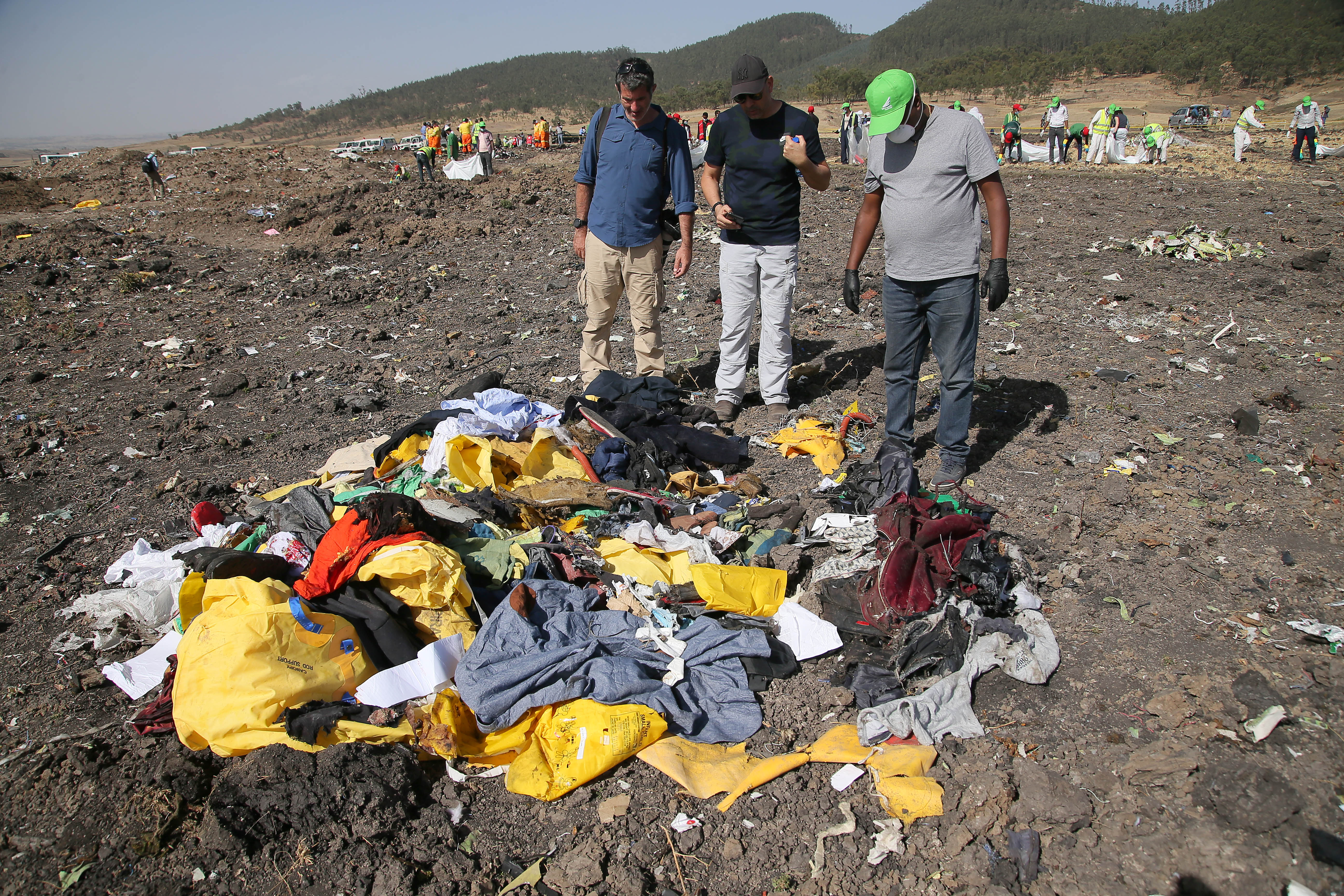 A man searching for personal effects belonging to his brother (center) who was a passenger on ET 302 speaks to a journalist and Recovery worker at the crash site of Ethiopian Airlines Flight ET 302 on March 12, 2019, in Bishoftu, Ethiopia. (Getty)