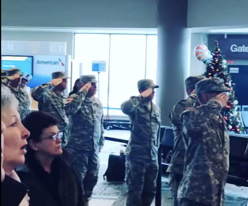 Active servicemen and women stand in attention and salute while travelers sing the national anthem (Source: Facebook)