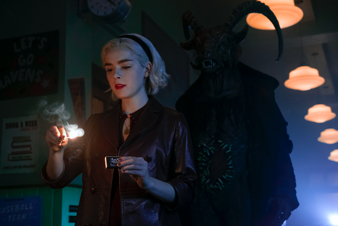 Sabrina strikes a match as a goat-headed creature looks on at Baxter High (Netflix)