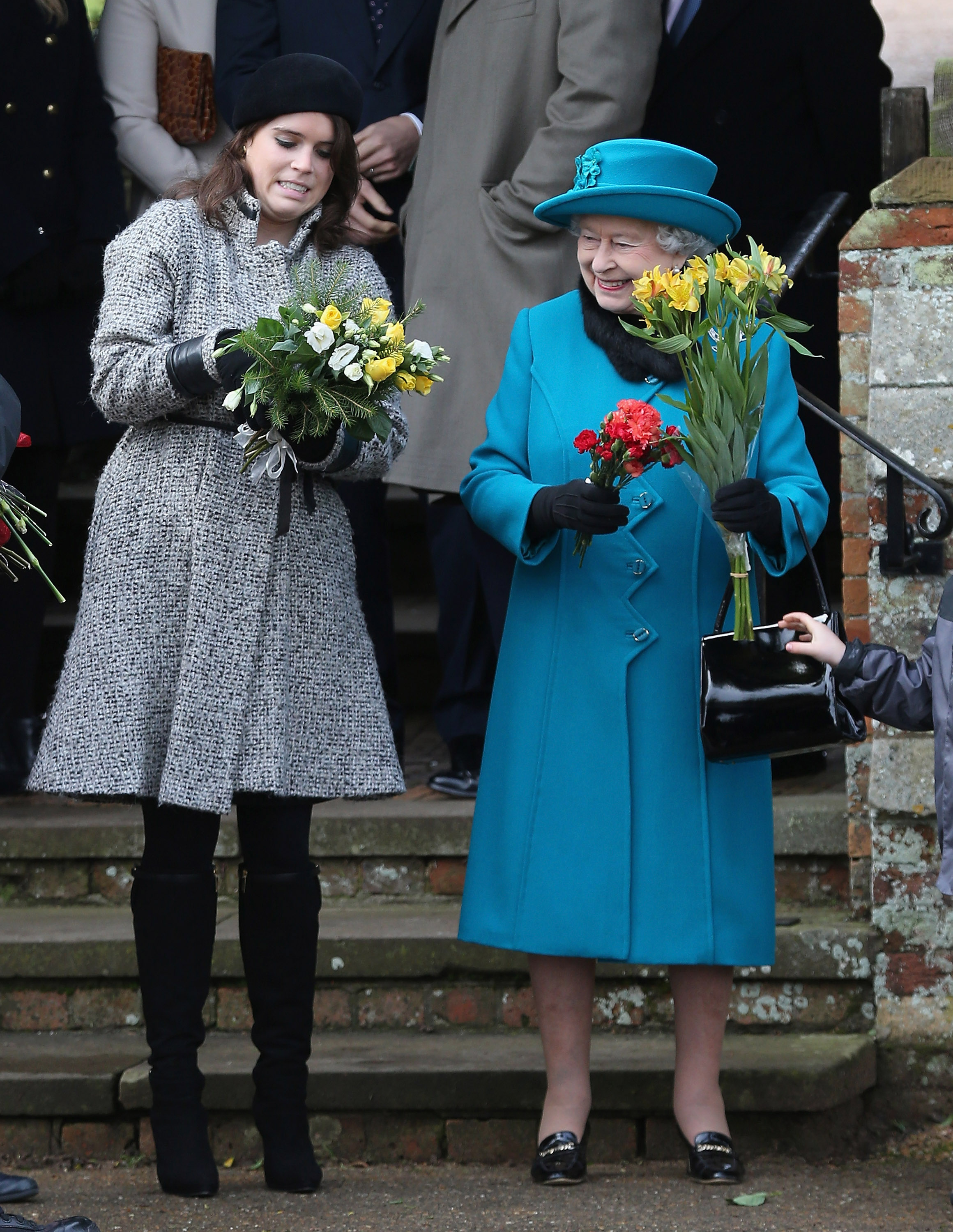 Queen Elizabeth II hands flowers to Princess Eugenie as they leave St Mary Magdalene Church after attending the traditional Christmas Day church service on December 25, 2012 in Sandringham, near King's Lynn, England.