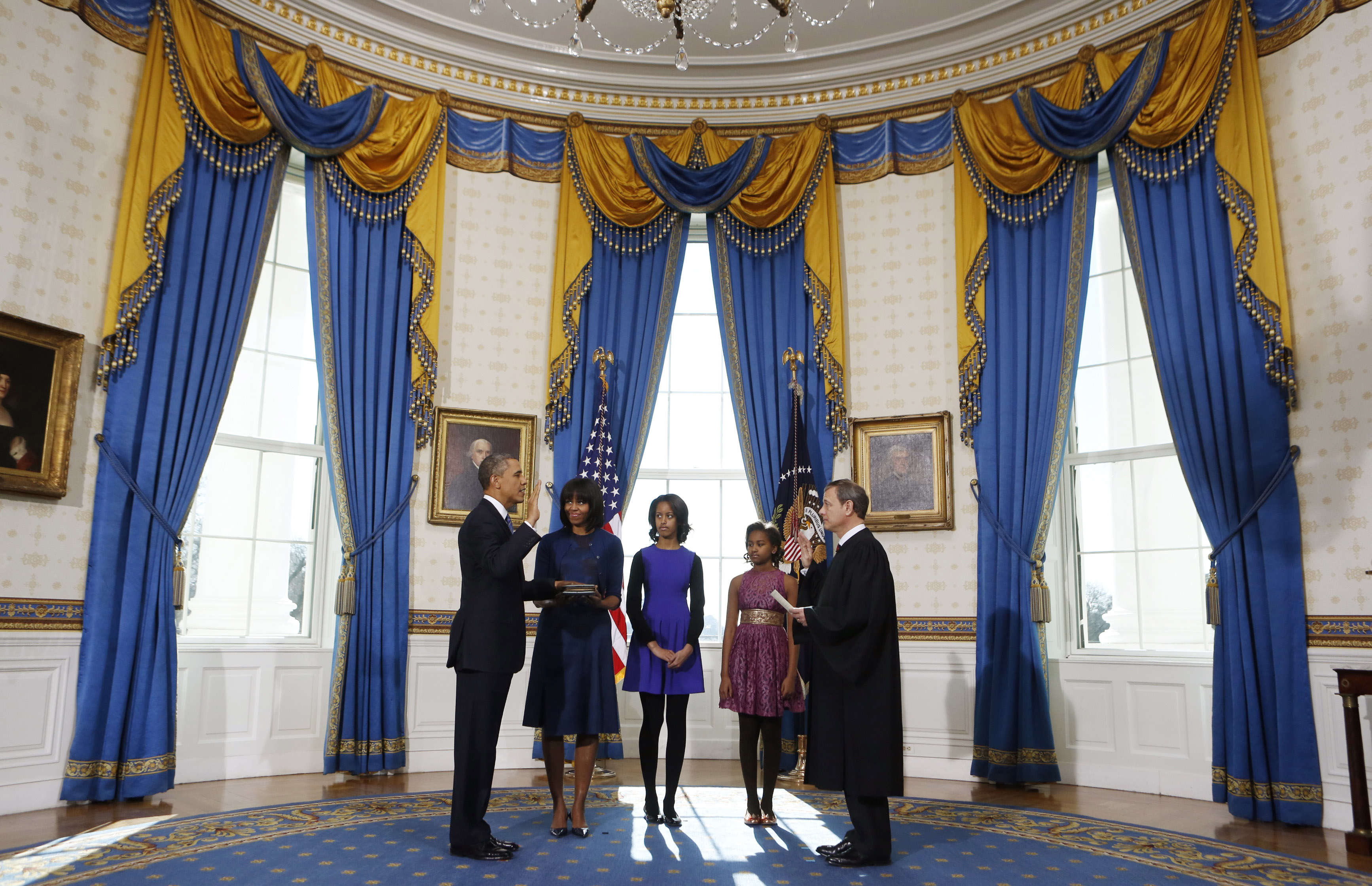WASHINGTON - JANUARY 20: U.S President Barack Obama (L) takes the oath of office from U.S. Supreme Court Chief Justice John Roberts (R) as first lady Michelle Obama (2nd L) holds the bible and daughter Malia (C) and Sasha looks on in the Blue Room of the White House January 20, 2013 in Washington, DC. Obama and U.S. Vice President Joe Biden were officially sworn in a day before the ceremonial inaugural swearing-in. (Photo by Larry Downing-Pool/Getty Images)