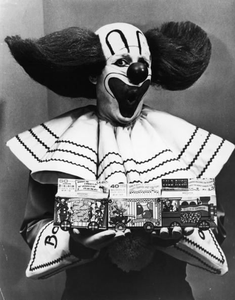 Promotional portrait of Bozo the Clown holding boxes of Bozo Express Bazooka bubble gum with a surprised expression on his face, circa 1965. (Photo by Hulton Archive/Getty Images)