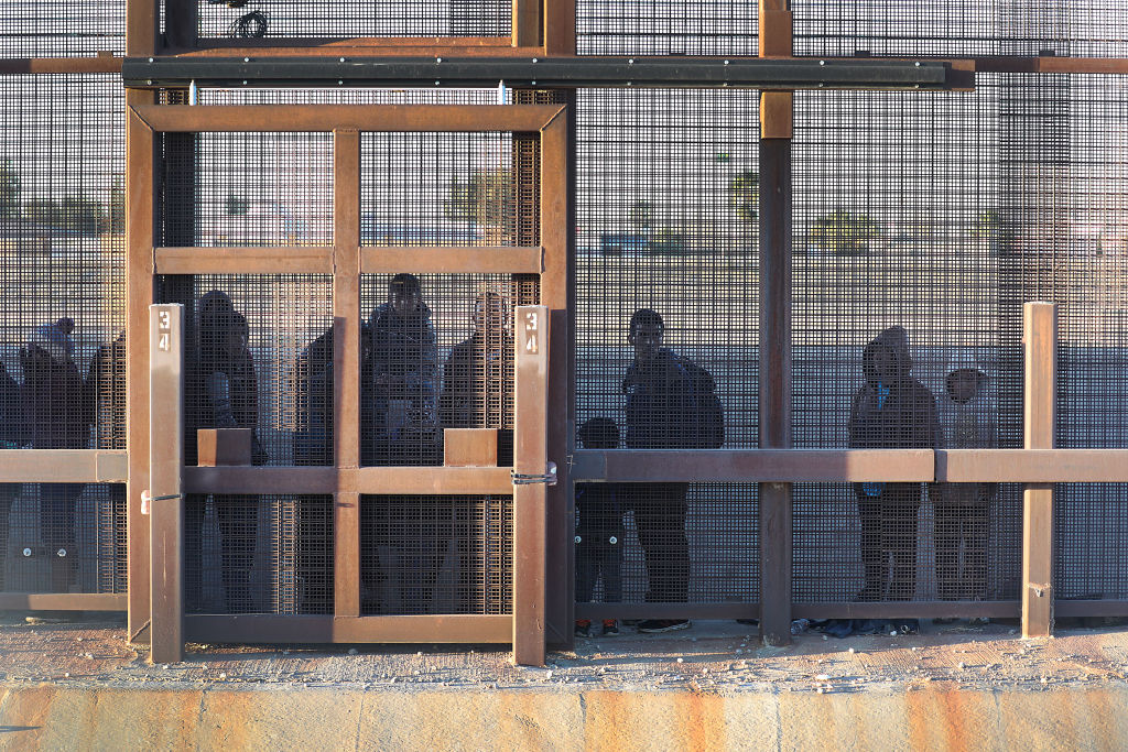 Migrants stand together along the U.S./Mexican border wall as they wait to turn themselves over to the U.S. Border Patrol on February 12, 2019, in El Paso, Texas. U.S. (Photo by Joe Raedle/Getty Images)