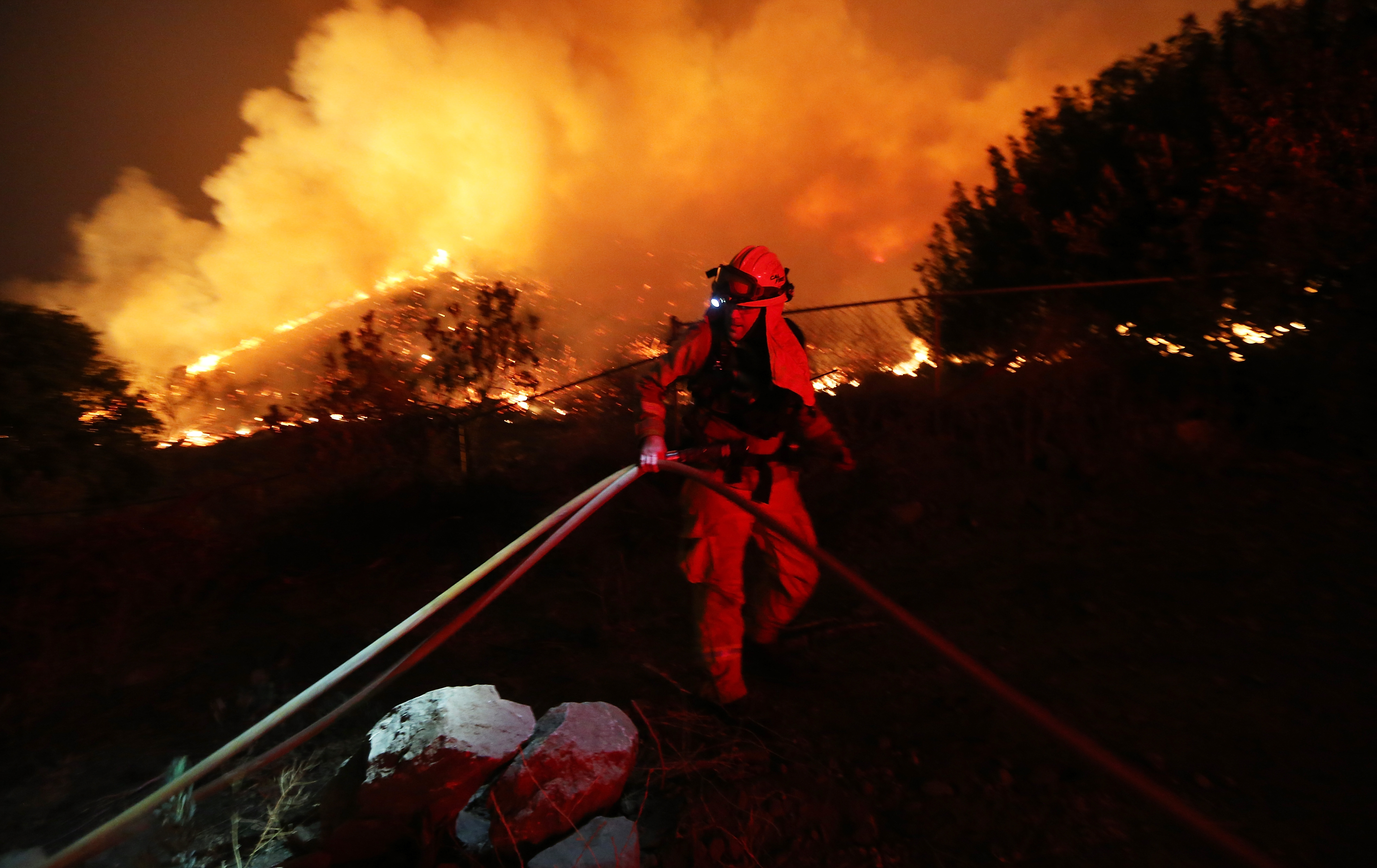 A firefighter works as the Holy Fire burns near homes on August 9, 2018 in Lake Elsinore, California. The fire continues to grow amidst a heat wave and has now burned 10,236 acres while remaining just five percent contained.