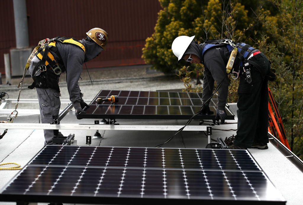 Workers install solar panels on the roof of a home on May 9, 2018, in San Francisco, California (Source: Getty Images)