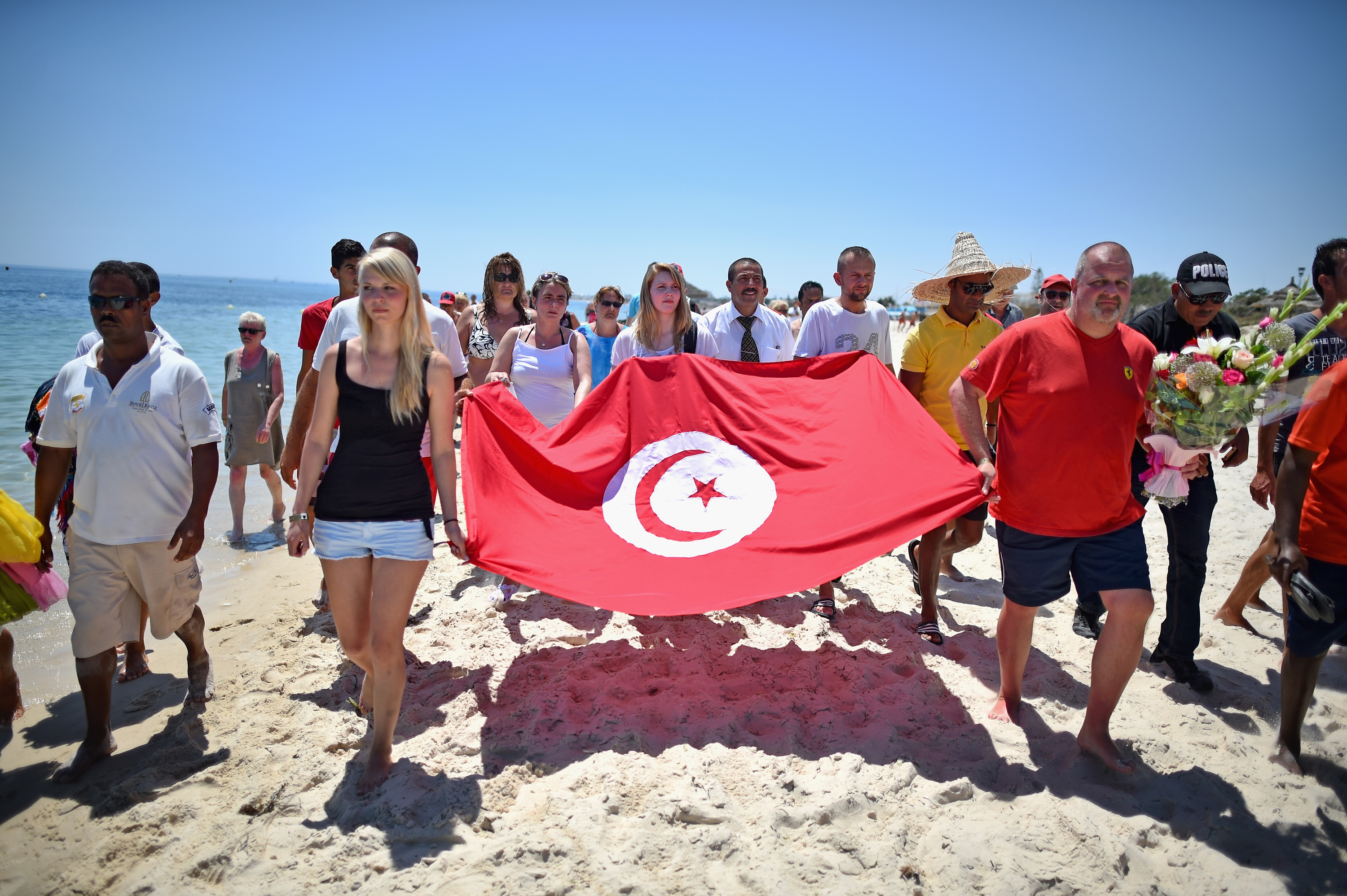Tourists carry a Tunisian flag along Marhaba beach where 38 people were killed on Friday in a terrorist attack on June 28, 2015, in Souuse, Tunisia. Sousse beaches remain quiet following Tunisia beach attack which left 38 dead, including at least 15 Britons around 1,00 tourist returned to the UK with more set to follow in the coming days. (Source: Jeff J Mitchell/Getty Images)