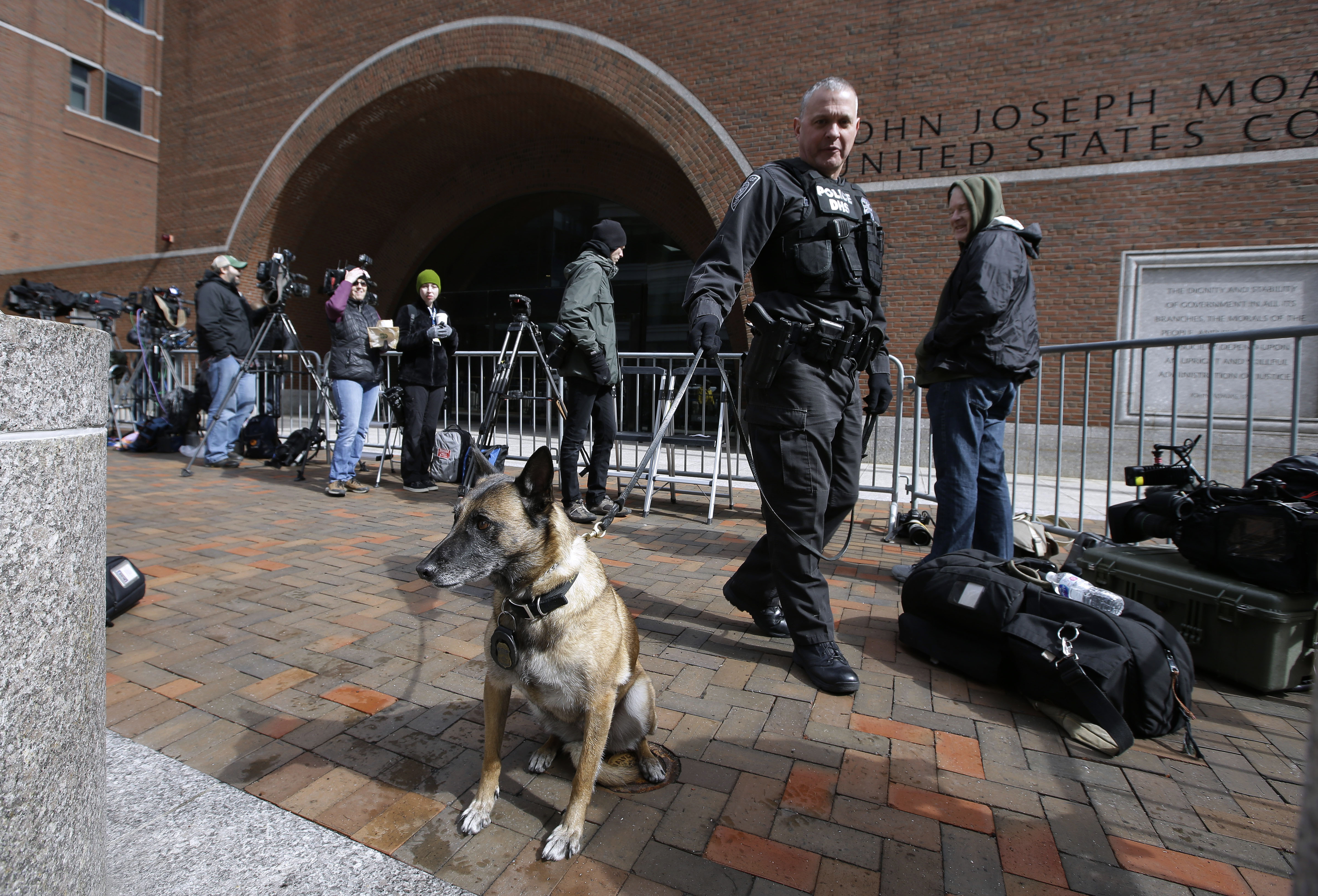 A Department of Homeland Security officer patrols with his K-9 outside federal court in Boston on Wednesday, April 3, 2019, where actress Felicity Huffman, actress Lori Loughlin and her husband, clothing designer Mossimo Giannulli are scheduled to attend an afternoon hearing in a nationwide college admissions bribery scandal. (AP Photo/Steven Senne)