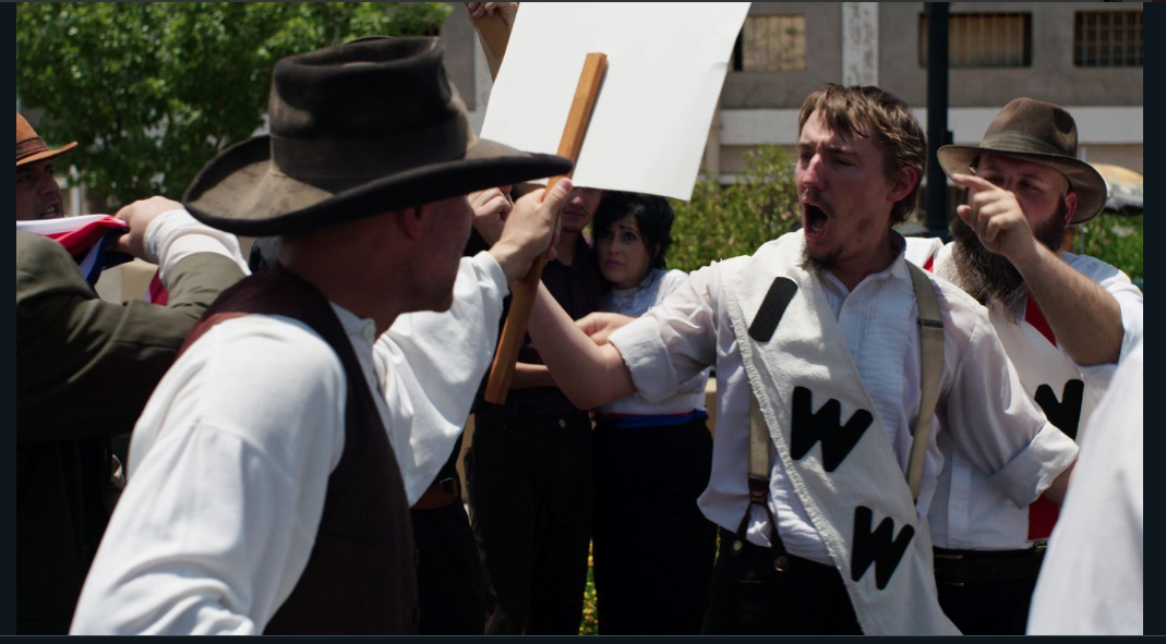 Townspeople playing the characters of striking miners from IWW protest on the streets of Bisbee, demanding safe working conditions.